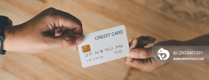 Womens hands holding a credit card hand over to service staff To pay for goods