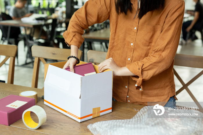 Startup small business woman owner packing cardboard box at workplace.