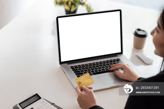 Close up of a business woman hand holding a credit card shopping online using laptop at the office. 