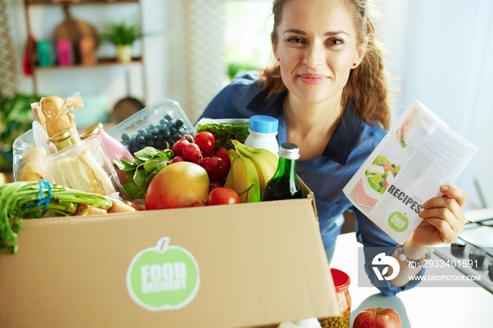 happy young female with food box in kitchen