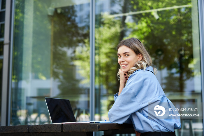 Portrait of young businesswoman working, using laptop while sitting outdoors. Corporate woman on vid