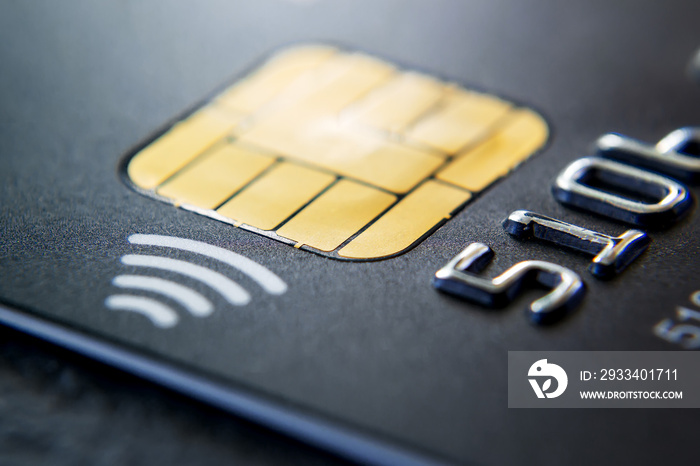 Close-up of black plastic credit card with chip and contactless pay technology. Macro photography of