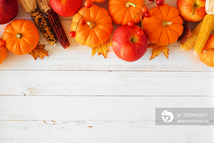 Autumn top border of leaves, pumpkins, apples and fall decor on a white wood background with copy sp