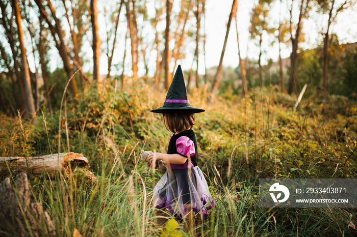 Girl walking disguised as a witch in the woods during Halloween