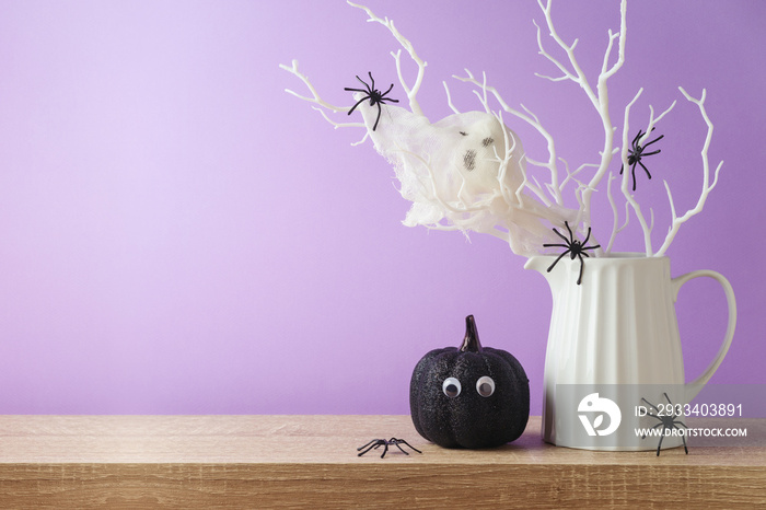 Halloween holiday decorations with glitter pumpkin, spiders and ghost on wooden table