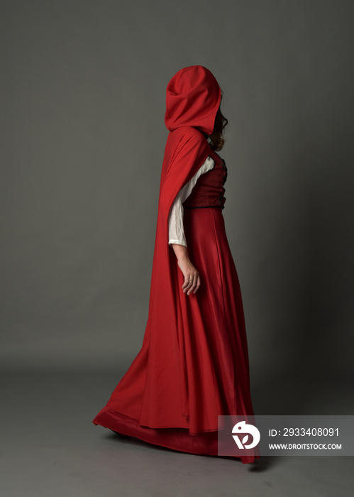 full length portrait of woman wearing red fantasy costume with cloak, standing pose on grey studio b