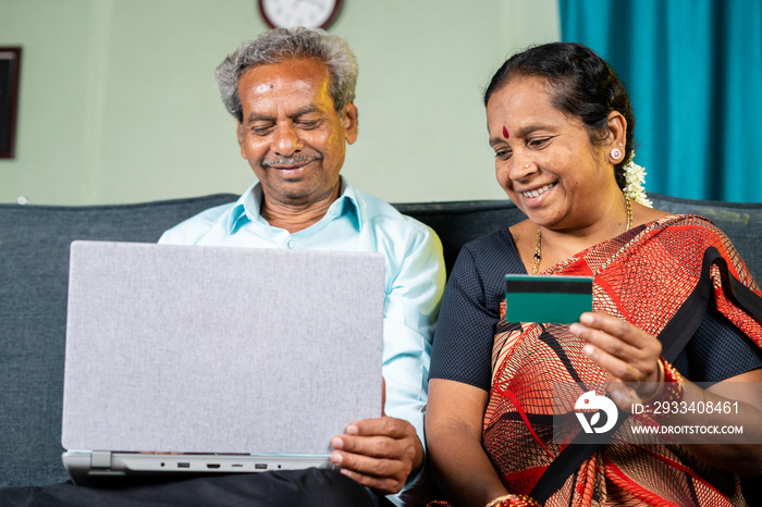 happy senior couple making online payment of e commerce purchase using credit card on laptop at home