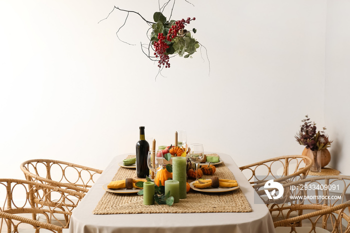 Autumn table setting with fresh pumpkins and leaves near light wall