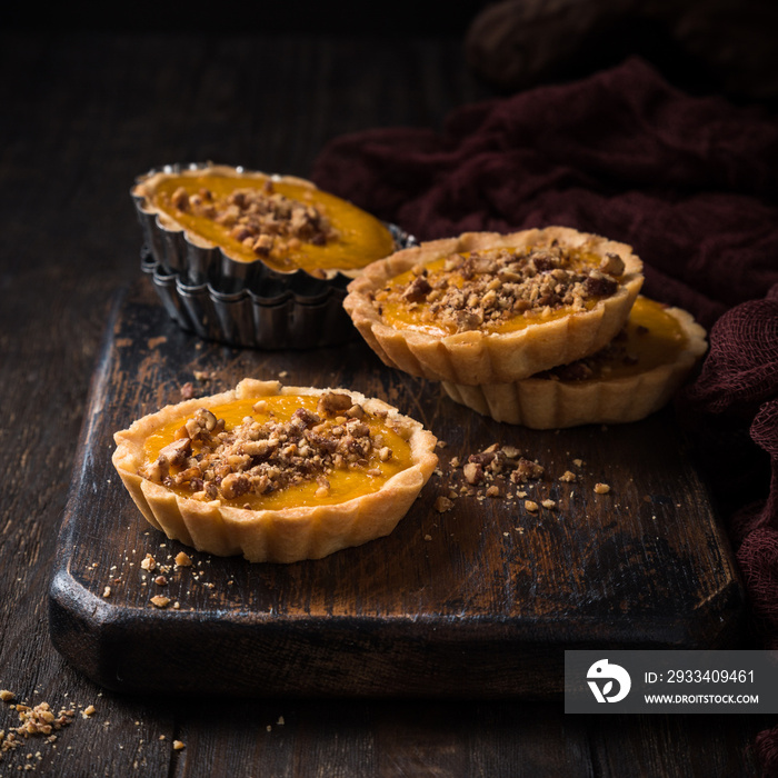 Pumpkin mini pie, tartlet made for Thanksgiving day on old wooden background. Healthy autumn food co