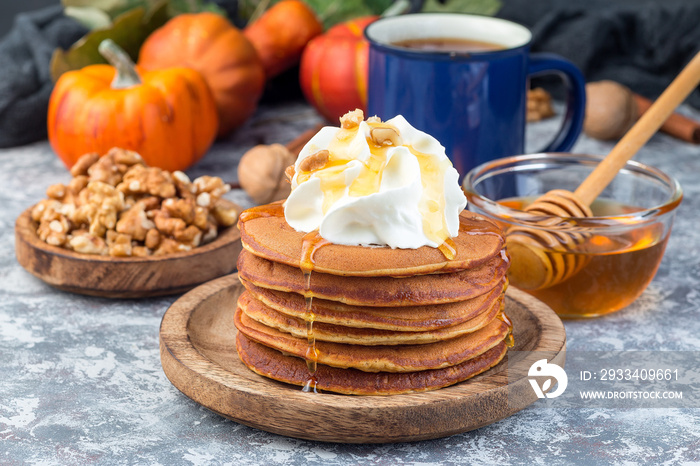 Delicious homemade pumpkin pancakes served with whipping cream, walnuts and honey, autumn decoration