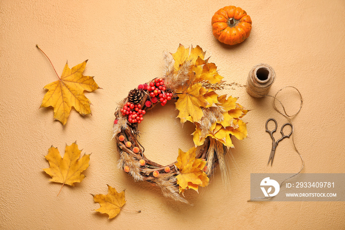 Beautiful autumn wreath with craft supplies on color background