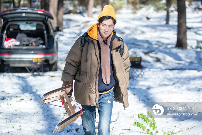 雪地上拿着雪橇的青年男人