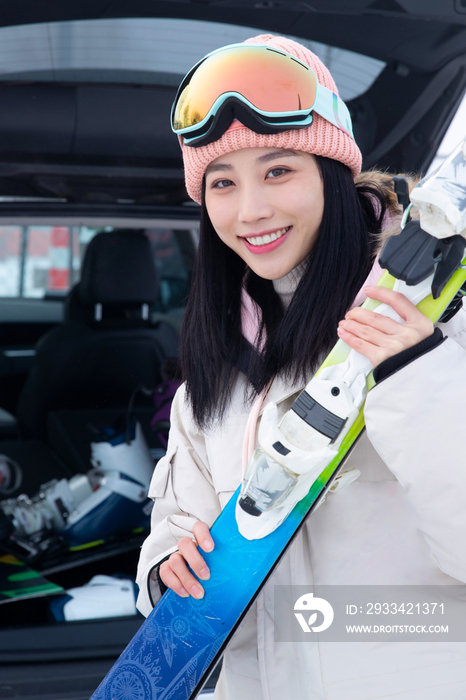 青年女人从汽车后备箱拿滑雪板