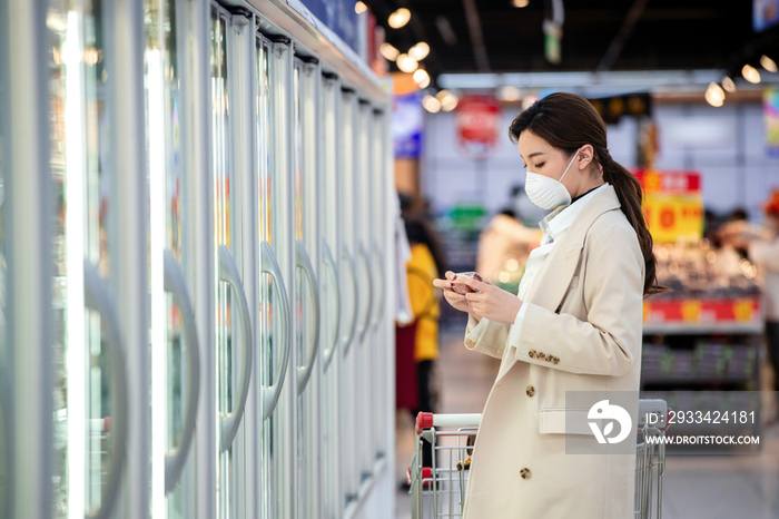 戴口罩的青年女人在超市购物