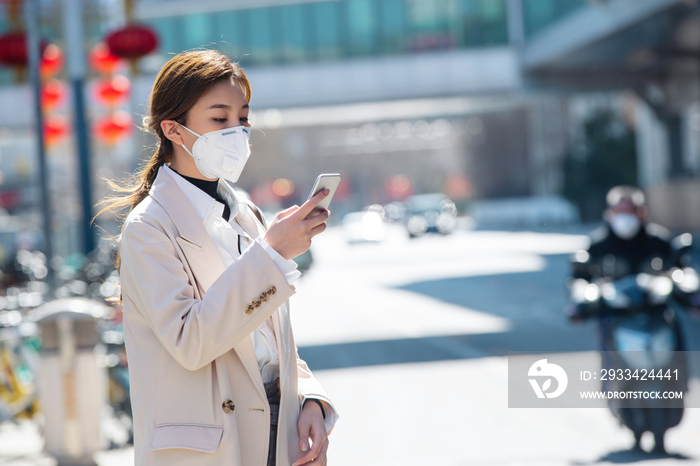 戴口罩的青年女人看手机