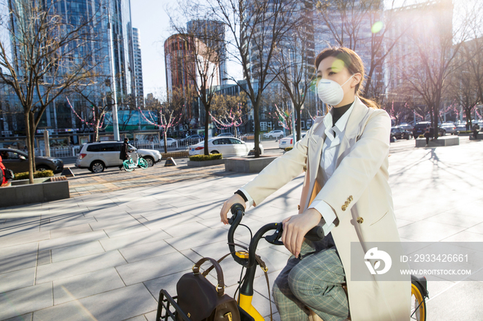 戴口罩的年轻女人骑共享单车