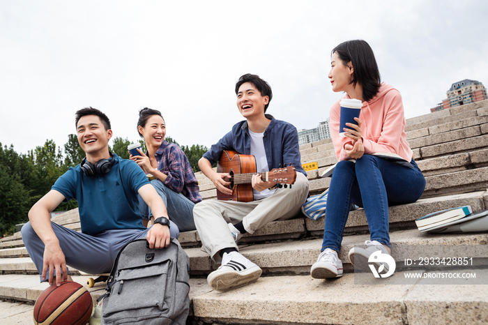 年轻的大学生坐在台阶上弹吉他