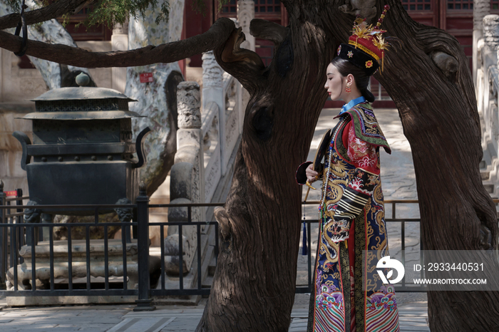 穿清宫服的青年女人站在古树下