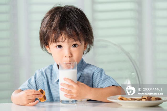 可爱的小男孩吃饼干喝牛奶