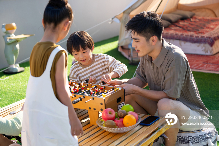 青年父亲和孩子在户外玩桌上足球