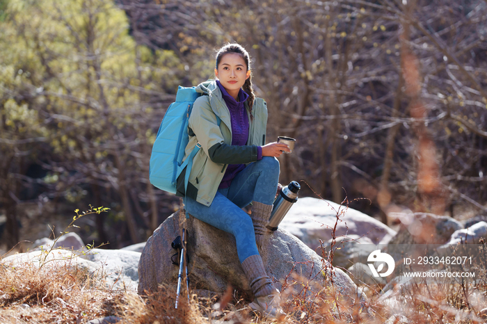 徒步旅行的青年女人坐在石头上休息