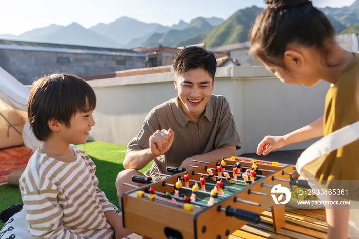 青年父亲和孩子在户外玩桌上足球
