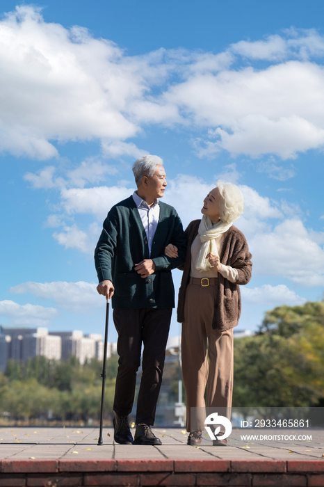 老年女人搀扶老伴在户外散步