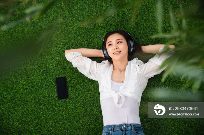 躺在草地上听音乐的青年女人