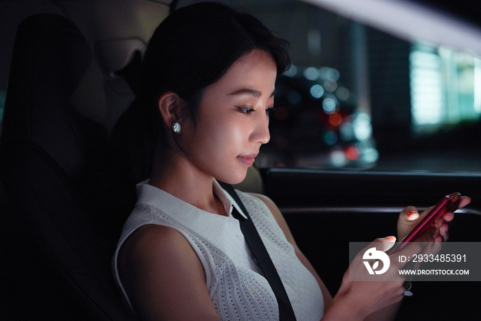 夜晚青年女人坐在汽车里使用手机