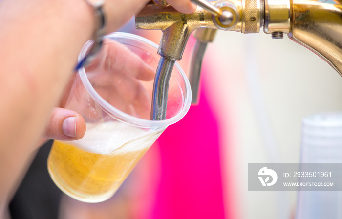 A bartender serving beer at a dispenser in plastic glasses