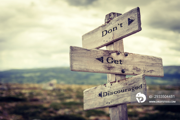 dont get discouraged text quote written in wooden signpost outdoors in nature. Moody theme feeling.