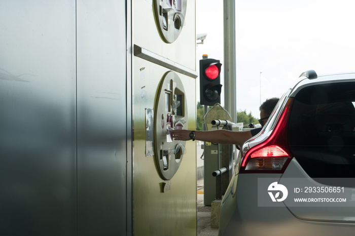 horizontal view of a man taking ticket from a toll booth on a French highway