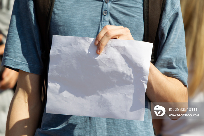 Man’s hands hold a blank white sheet of paper.