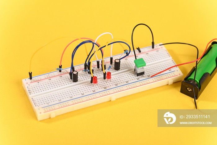 Breadboard with electrical elements, on yellow background.