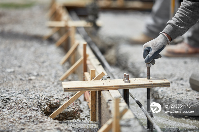 Construction Worker plancing Anchor Bolt into Wet Cement