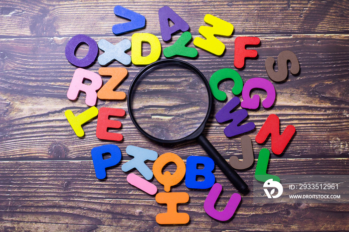 Multicolored English letters spread on the wooden floor. Magnifier and English Alphabet with English Learning Concepts, The concept of thinking development, grammar