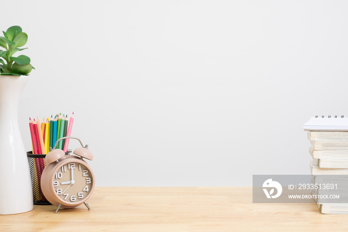 Office desk with pencils, plant vase, alarm clock and book. work copy space.