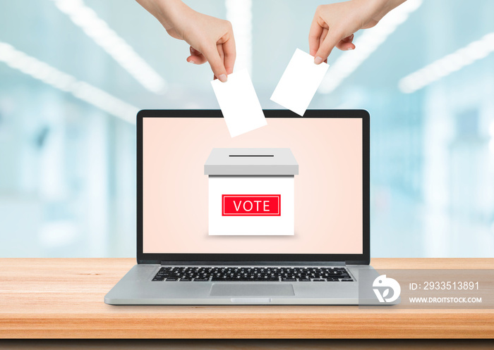 Online Voting Concept : Hand holding and putting voting paper card in ballot box on laptop screen.