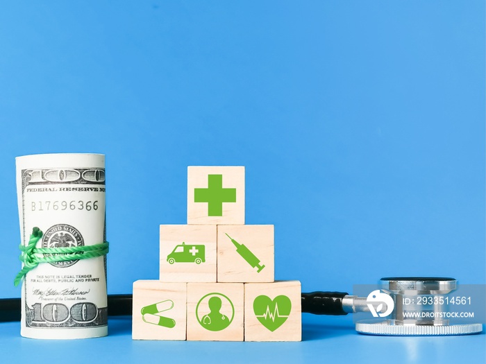 Medical cost and insurance concept. Wooden cubes with medical icons, fake money and stethescope.