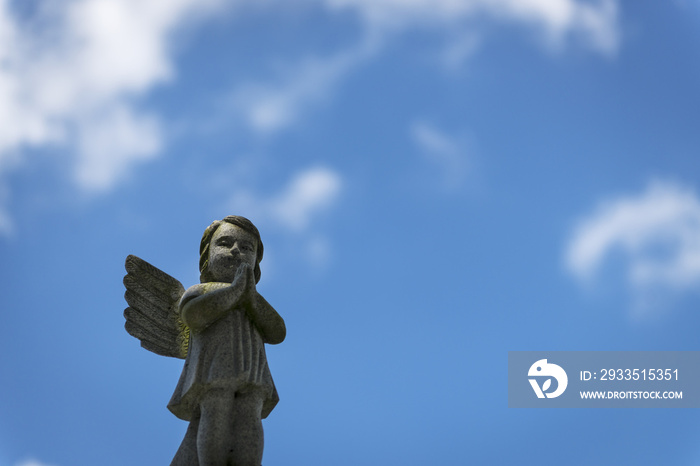 A sad angel against the blue sky in a cemetery in the city of New Orleans, Louisiana, USA