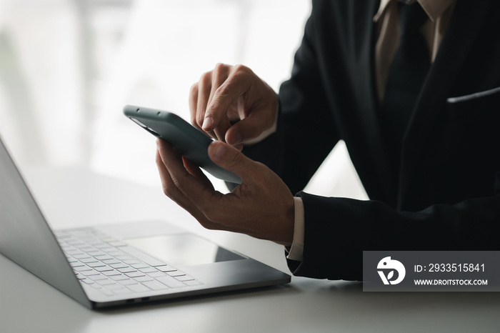 Business man looking at financial information from a mobile phone, he is checking company financial documents, he is an executive of a startup company. Concept of financial management.