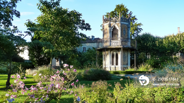 View on green public garden (jardin public, Cognac) with gothic tower against blue summer sky (focus on tower)