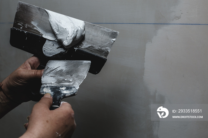 Worker working manual with wall plastering tools inside a house