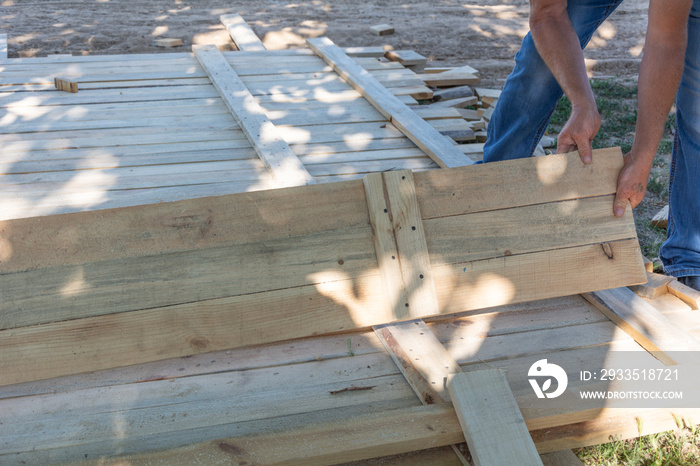 Man building a wooden fence. Workers pick up wooden boards for the fence formwork. Wooden formworks for concrete at construction site.