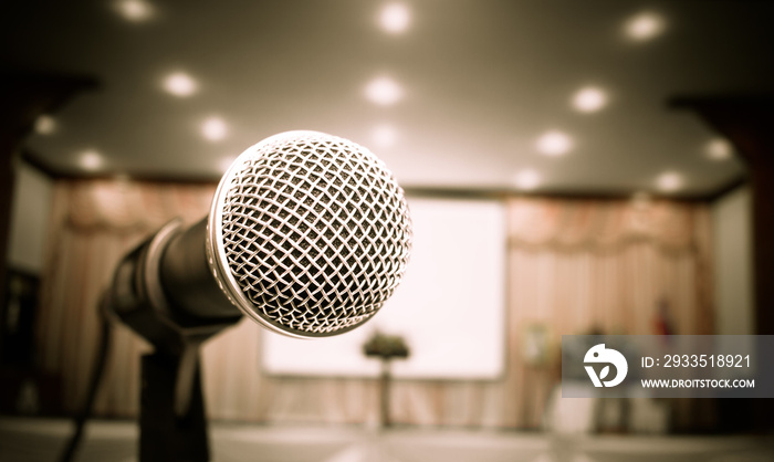 Microphone on abstract blurred of front podium and speech in seminar room or speaking conference hall light, Event meeting bokeh background, black and white tone