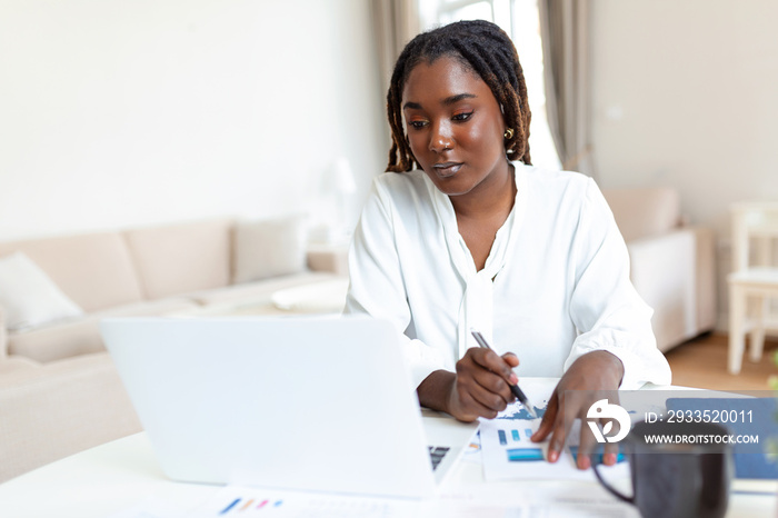 Female businessmen in casual wear work at the desk about accounting and business plan analysis. Young black woman at her desk in an office. Graphs and charts