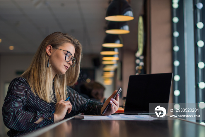 Young business lady communicates on social networks on the phone in between work