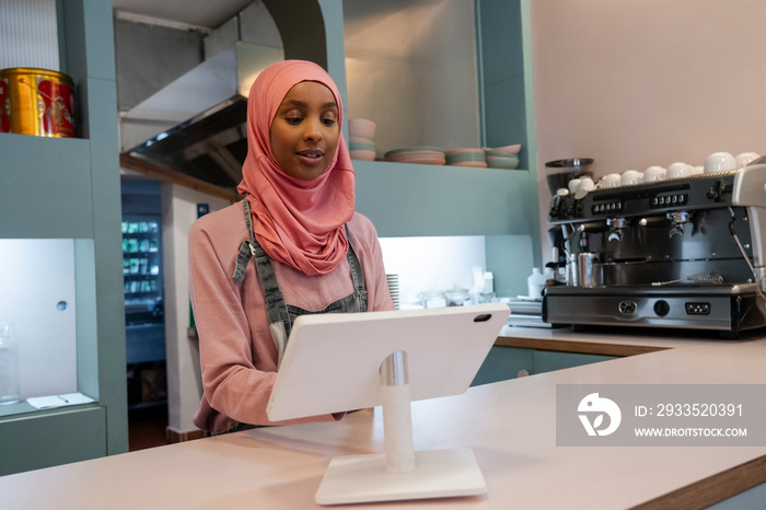 Young woman in hijab working in cafe