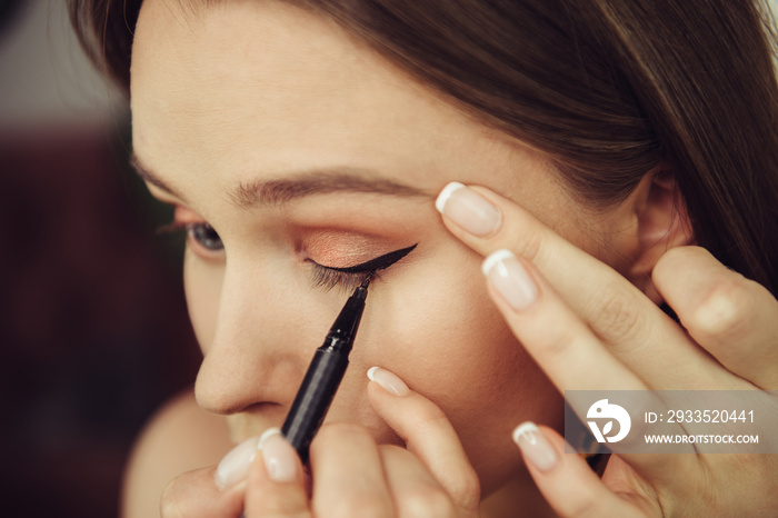 Woman doing makeup and painting black arrows