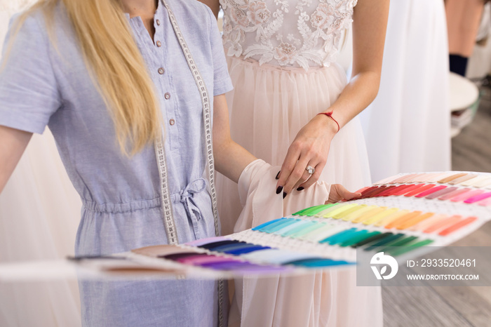 Fitting a wedding dress in the office of a seamstress and choose the color of the fabric for the dress. The bride and the designer of wedding dresses try on a dress